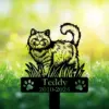 Black cat memorial garden stake reading “Teddy 2010-2024” with paw prints, displayed in grass with flowers