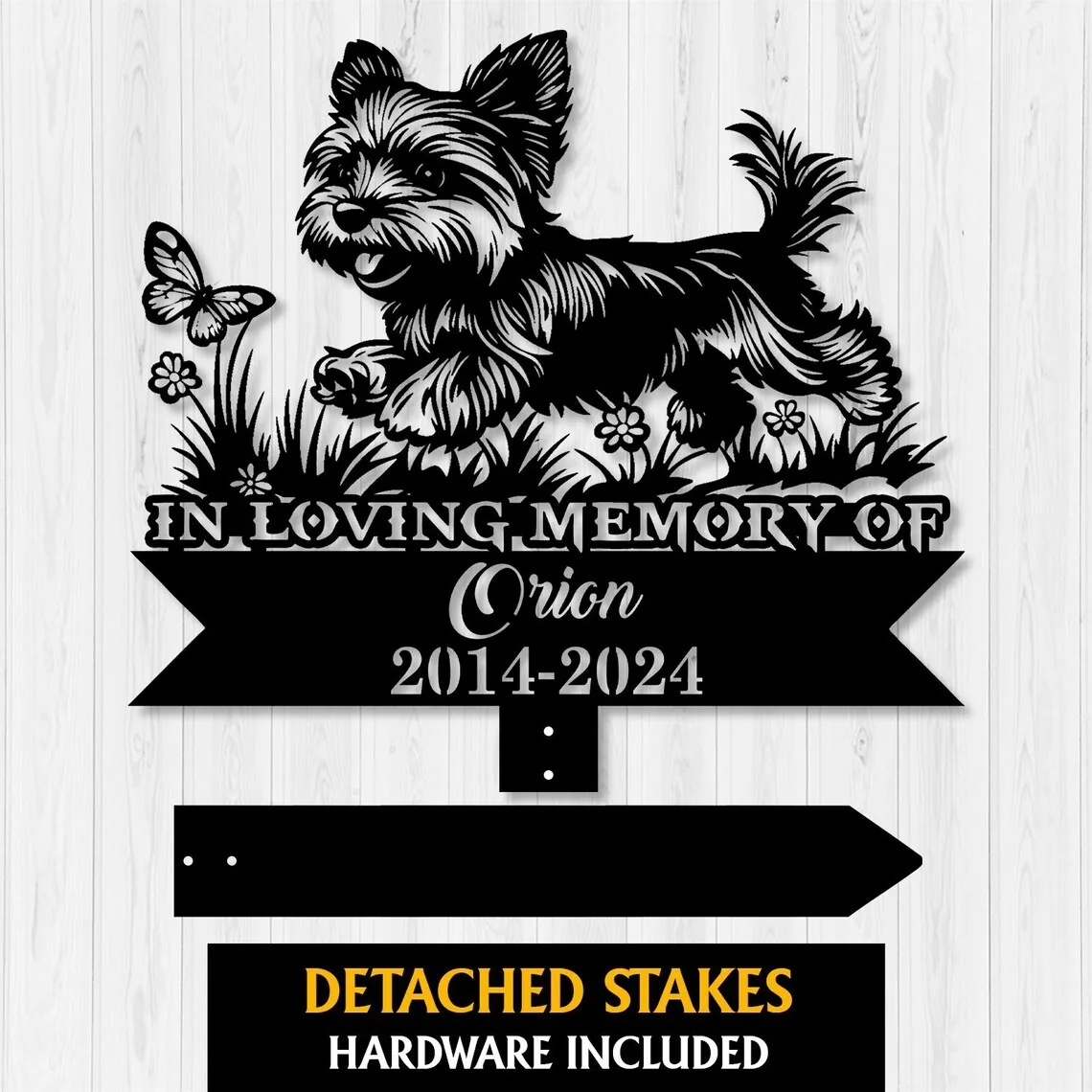 A memorial plaque featuring a playful dog silhouette, with text honoring 'Orion 2014-2024' and detached stakes included.