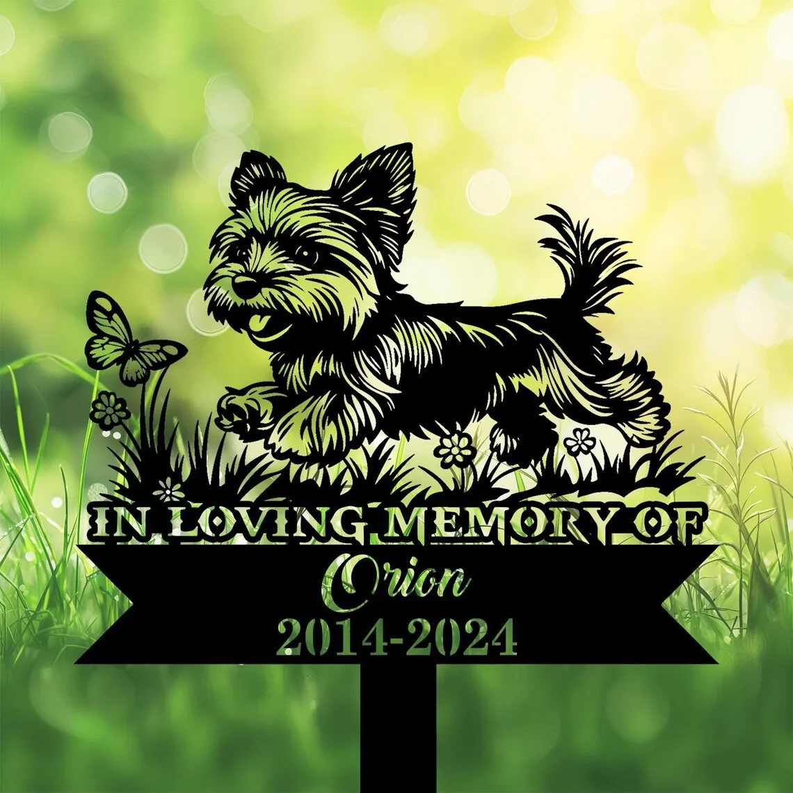 A memorial sign featuring a playful dog and butterfly, with text 'In Loving Memory of Orion 2014-2024'.