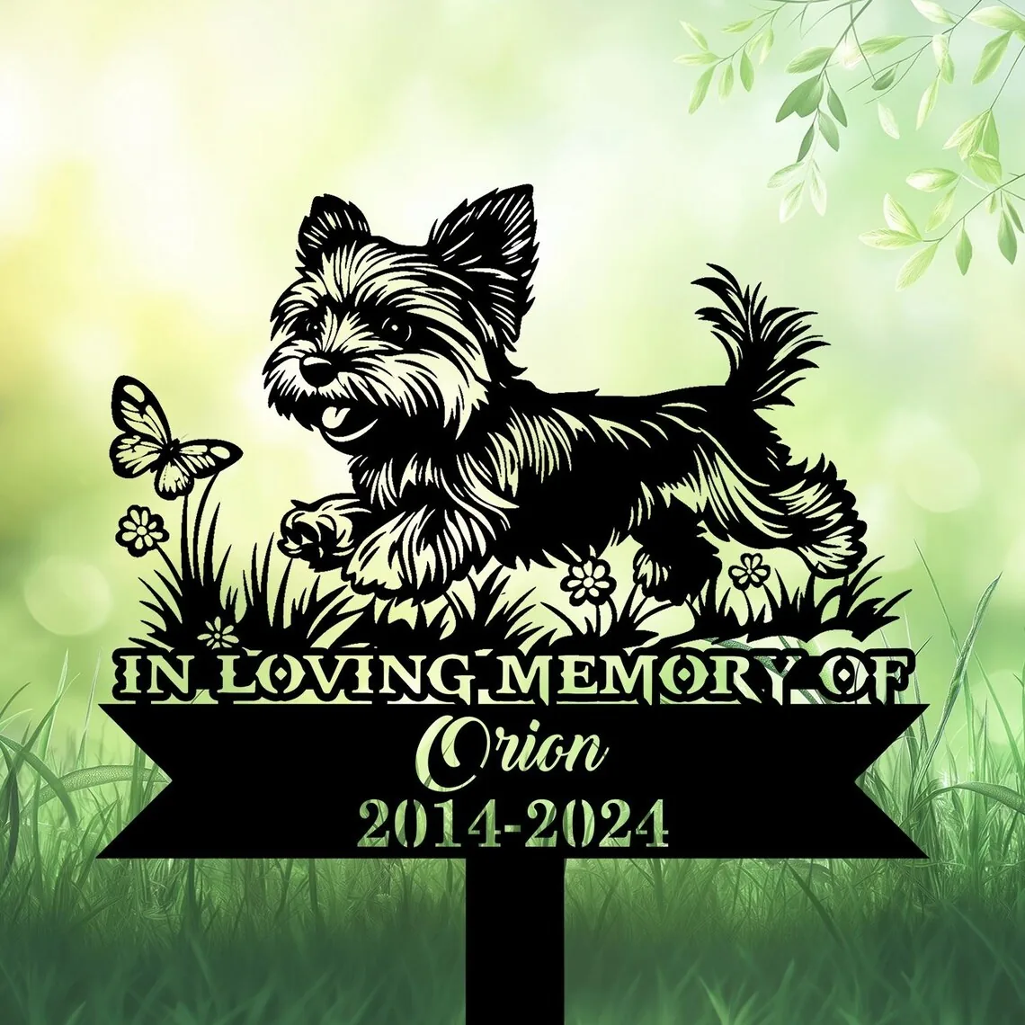 A memorial sign featuring a playful dog with a butterfly and flowers, reading 'In Loving Memory of Orion 2014-2024'.