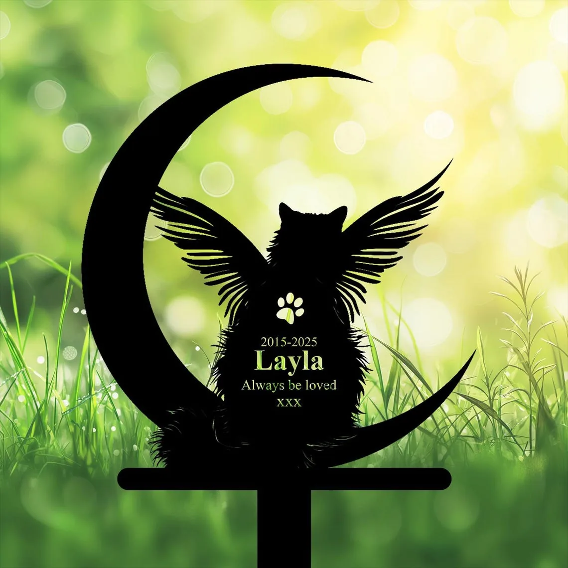 A silhouette of a cat with wings on a crescent moon, set against a blurred green background.