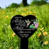 Heart-shaped black memorial stake in a wildflower meadow reading: "When you believe beyond what your eyes can see, signs from Heaven show up to remind you love never dies" with name Jesse Williams 1943–2022 and a hummingbird and flowers illustration