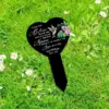 Black heart-shaped memorial garden stake in grass with white daisies, hummingbird and flowers illustration, memorial text for Jesse Williams 1943–2022