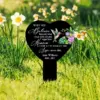 Heart-shaped black memorial stake in grassy garden among daffodils reading: “When you believe beyond what your eyes can see, signs from Heaven show up to remind you love never dies” with name Jesse Williams 1943–2022 and hummingbird floral design.