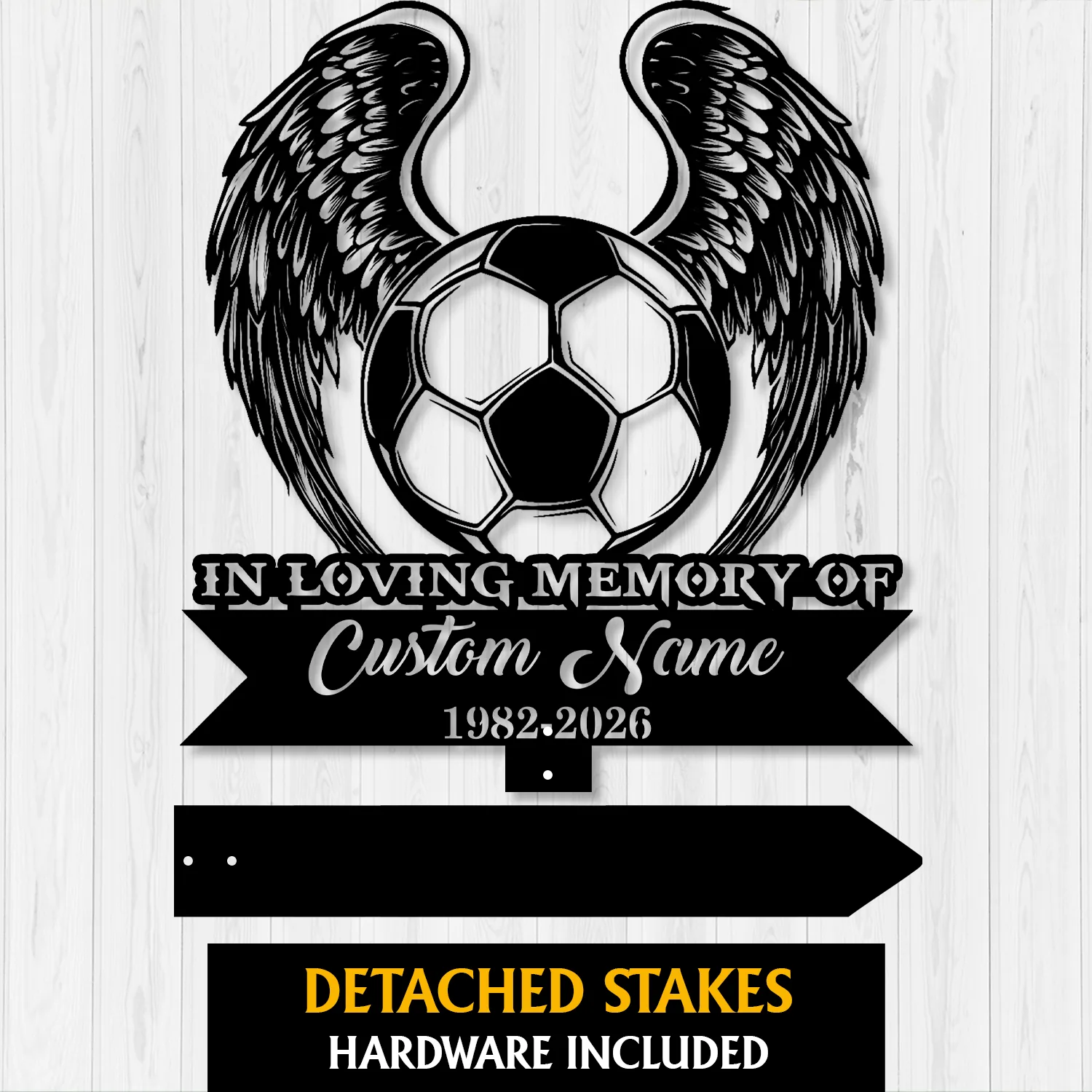 Black metal memorial sign showing a soccer ball with angel wings, banner reading "In Loving Memory of Custom Name" and dates 1982-2026 on a light wood background