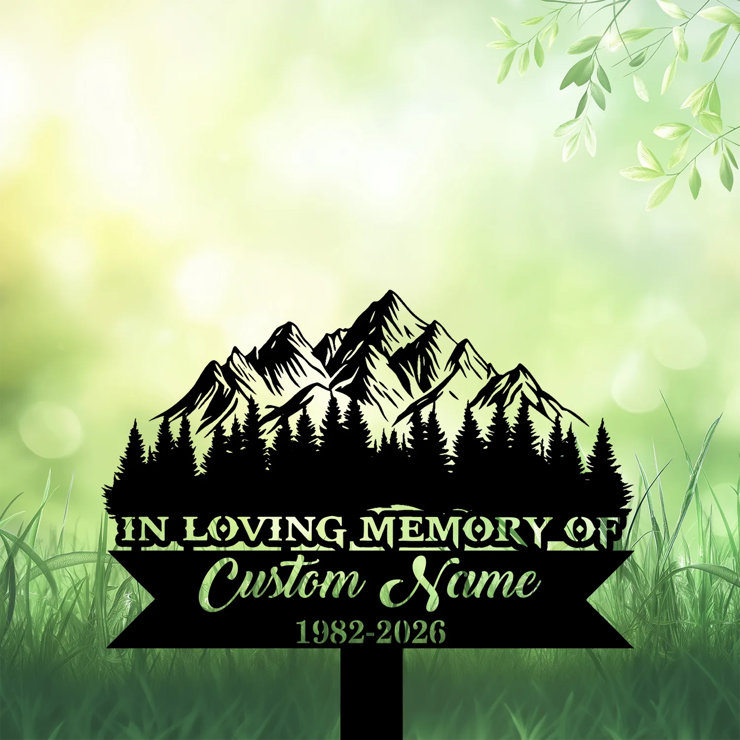 11b Black silhouette memorial sign with mountain and pine trees reading "In Loving Memory of" and placeholder "Custom Name" with dates 1982-2026 on a soft green grassy background