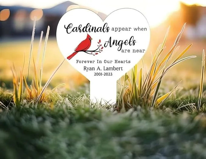 123 Heart-shaped memorial yard sign reading “Cardinals appear when Angels are near – Forever In Our Hearts Ryan A. Lambert 2001-2023” with a red cardinal image in grass