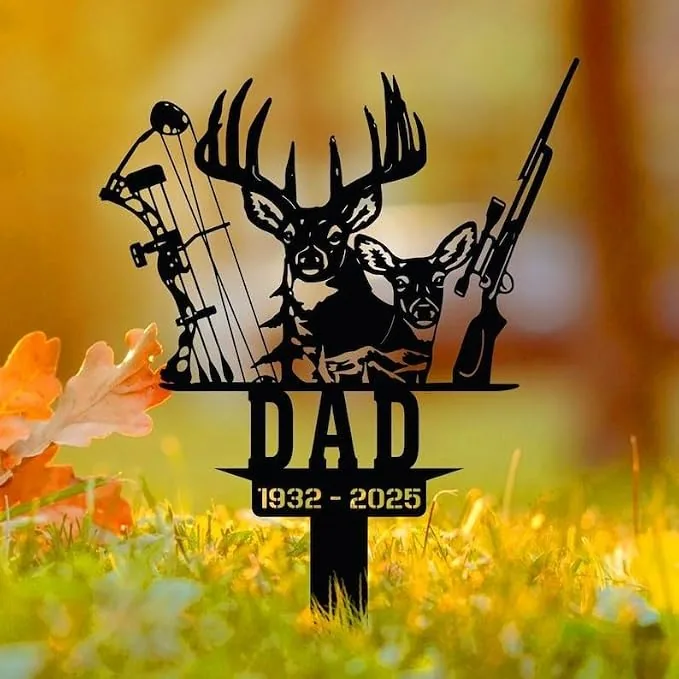 Black metal yard memorial sign with deer, hunting bow and rifle above the word DAD and dates 1932 - 2025 placed in grassy yard