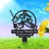 Black metal memorial lawn sign showing a hockey goalie silhouette, text 'In Loving Memory Of', 'CUSTOM NAME', and years '1950 - 2024' against a grassy field and bright sky with yellow flowers