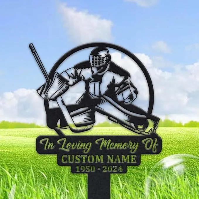 Black metal memorial yard sign depicting a hockey goalie in gear and stick, text reading "In Loving Memory Of" with placeholder "CUSTOM NAME" and dates "1950 - 2024", set outdoors on green grass under a blue sky.