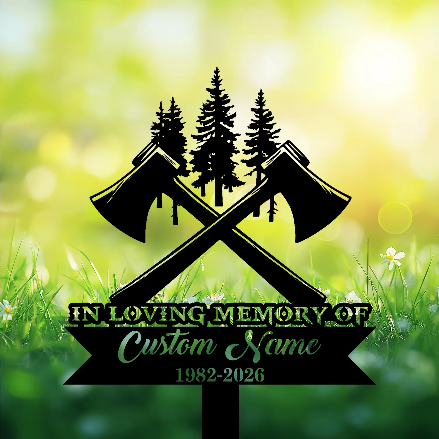 Black memorial sign with crossed axes and pine tree silhouettes reading "In Loving Memory" and "Custom Name 1982-2026" against sunlit grassy background