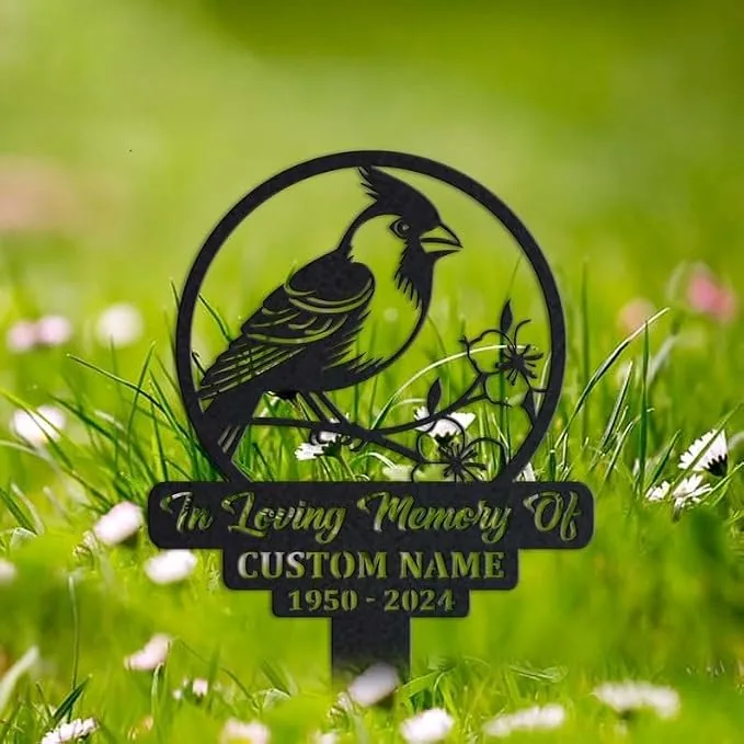 Black metal memorial garden stake with a bird and flowers, engraved text reading "In Loving Memory Of" and placeholder "CUSTOM NAME 1950 - 2024", set in grassy lawn
