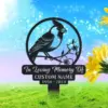 Metal memorial yard sign with a perched bird and flowers, reading "In Loving Memory Of CUSTOM NAME 1950 - 2024," displayed on a grassy lawn with bright sky and sunflowers nearby.
