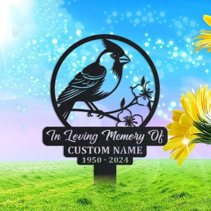Metal memorial yard sign with a perched bird and flowers, reading "In Loving Memory Of CUSTOM NAME 1950 - 2024," displayed on a grassy lawn with bright sky and sunflowers nearby.