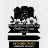 Black metal memorial sign shaped like a camera with flowers, reading "IN LOVING MEMORY OF" and a cursive placeholder "Custom Name" with dates 1982-2026, on a light wood background
