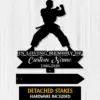 Black silhouette of a martial artist in a fighting stance above text reading "In Loving Memory Of" and placeholder "Custom Name 1986-2026" on a white wood background