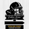 Black metal memorial sign showing a football helmet and ball with text "In Loving Memory Of" and customizable name and dates on a light wood background