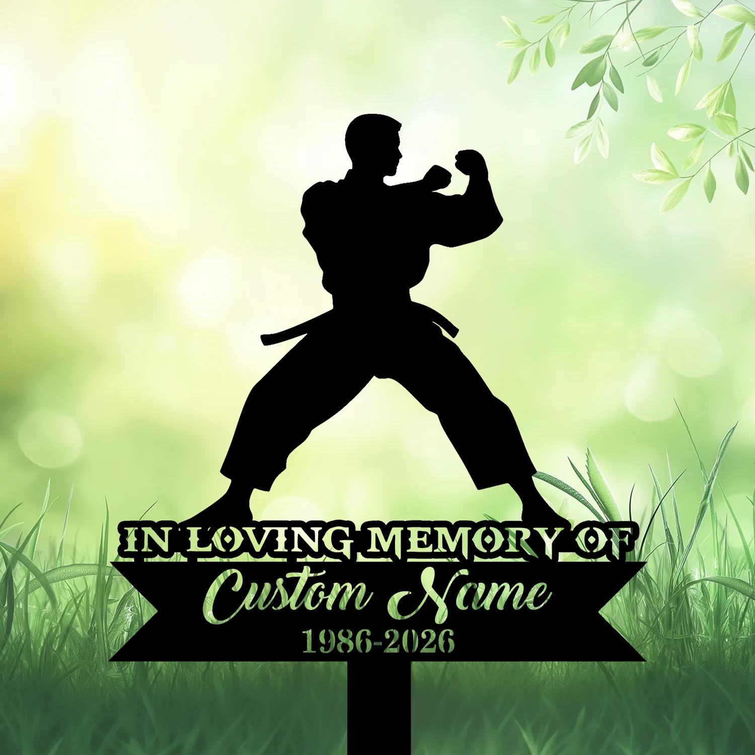 Silhouette of a martial artist in a wide stance above a memorial sign reading "IN LOVING MEMORY OF" with placeholder "Custom Name" and dates "1986-2026" on a grassy, green bokeh background
