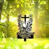 Black memorial cross sign in a sunlit forest clearing reading "In Loving Memory of CHRISTINA 1980-2025" with praying hands and floral illustrations