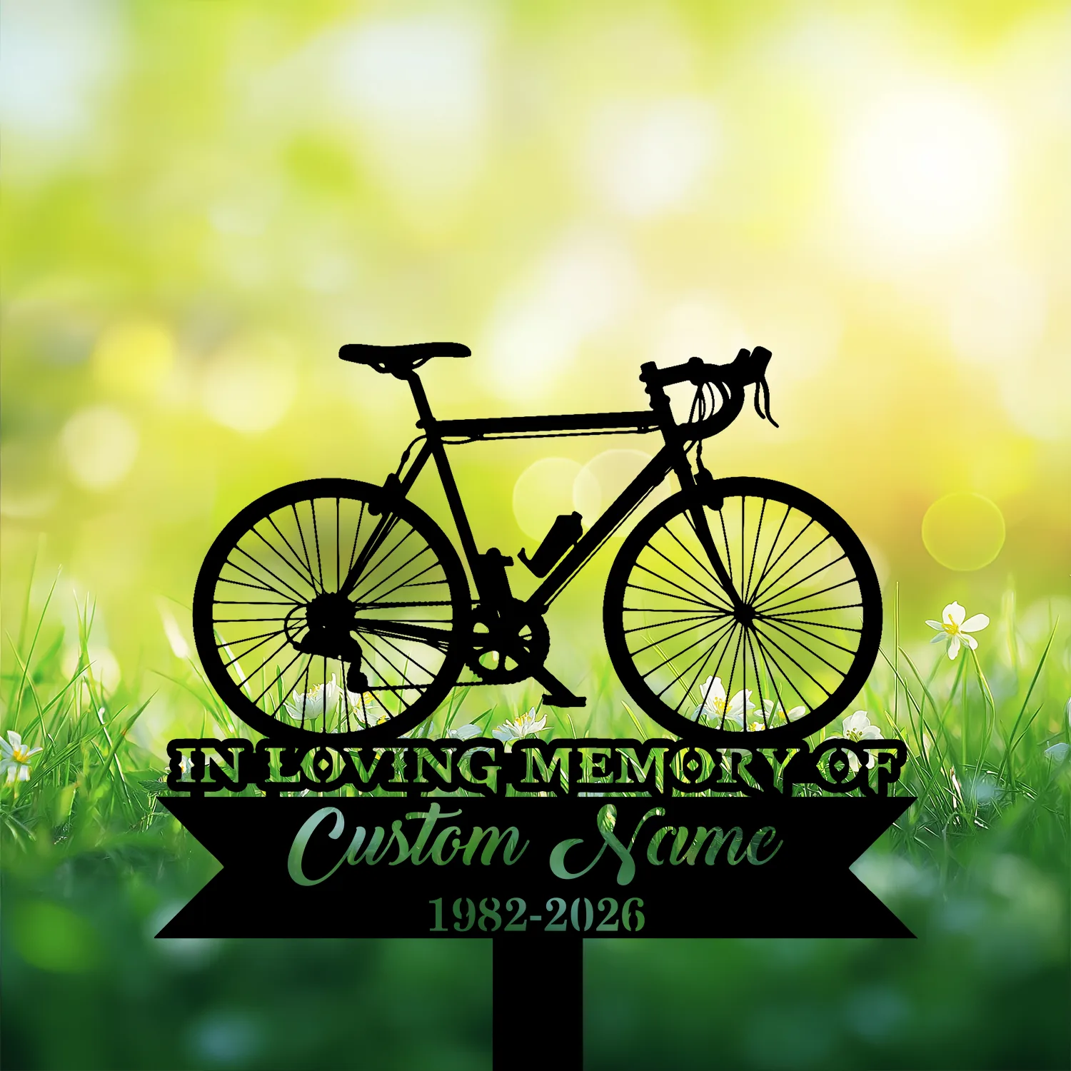 6-3 Black silhouette memorial sign of a road bicycle over grass and flowers with text placeholders "IN LOVING MEMORY OF", "Custom Name" and dates "1982-2026" against a sunny bokeh background