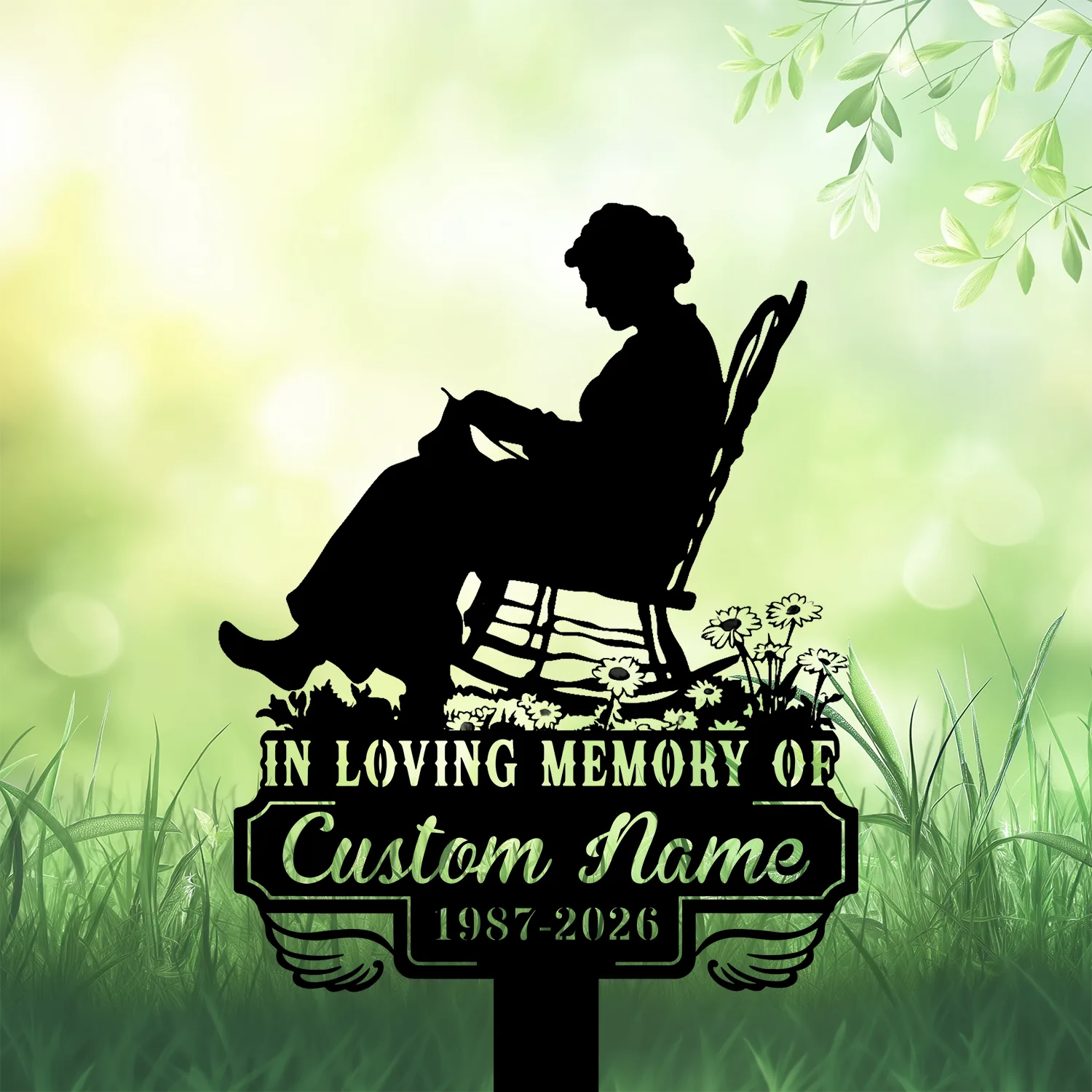 6b-2 Black silhouette memorial lawn sign of an elderly woman sitting in a rocking chair reading, flowers and grass foreground, text reads "In Loving Memory of Custom Name 1987-2026" against a soft green bokeh background
