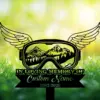 7-4 Black memorial sign shaped like winged goggles with mountain scene inside, text 'IN LOVING MEMORY OF', placeholder 'Custom Name' and dates '1982-2026' against sunny grassy background