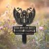 Black metal memorial sign with a winged motorcycle and text “Riding With The Angels Robert Johnson 04/27/1967 - 11/08/2025” placed among sunlit wildflowers