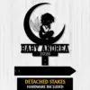 Black silhouette nursery sign showing a winged baby sitting on a crescent moon with text "BABY ANDREA" and year "2026" on a light wood background