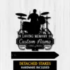 Black silhouette memorial sign of a drummer and drum set mounted on white wood background reading "In Loving Memory of Custom Name 1987-2026" with detached stakes shown