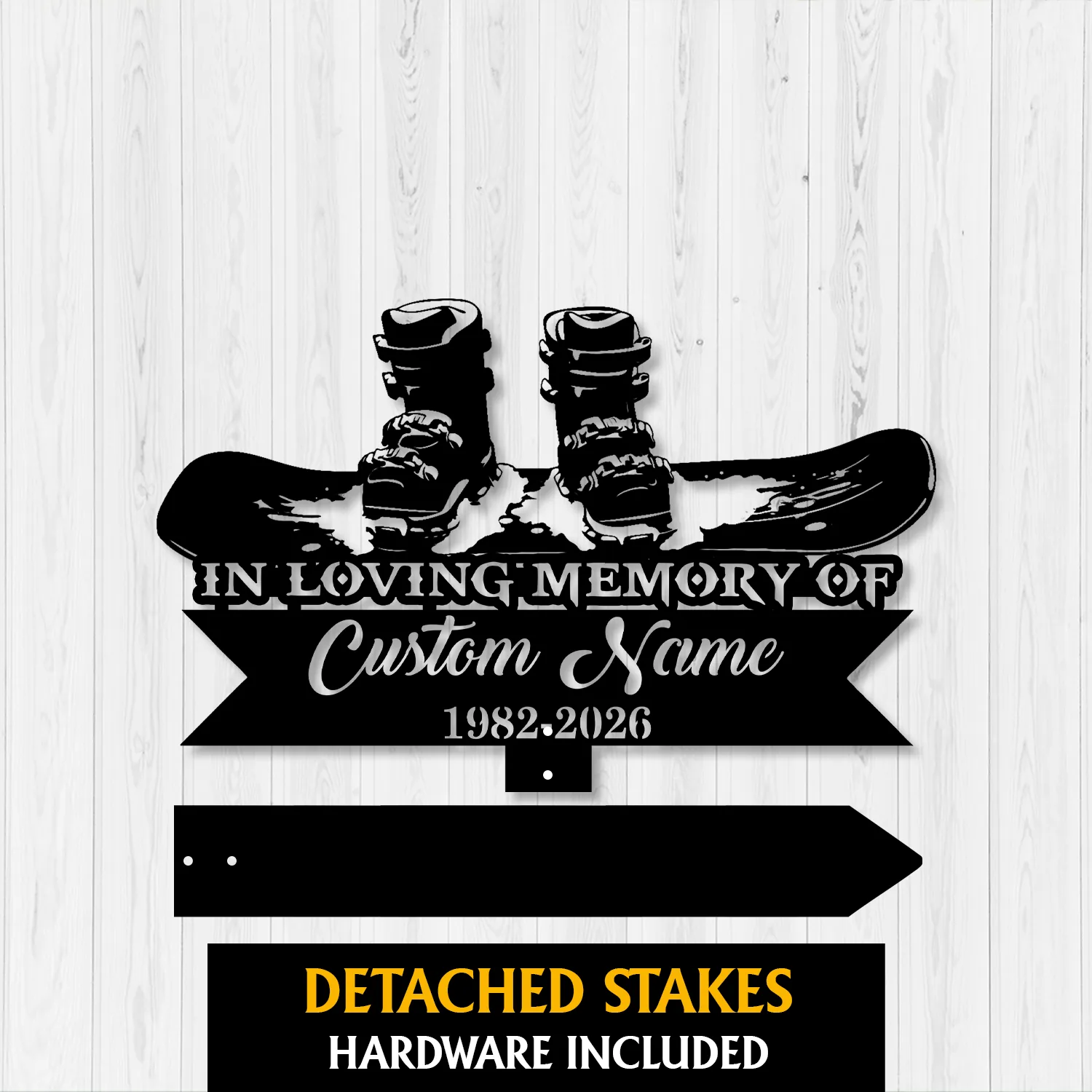 Black metal memorial sign with snowboard and boots graphic, text reading "In Loving Memory of" and placeholder "Custom Name" with dates 1982-2026 on a light wood background