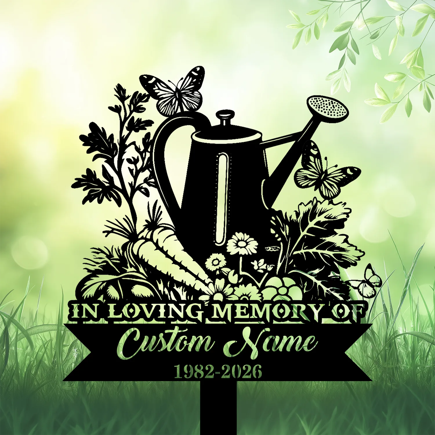 9b-2 Black silhouette memorial garden sign with a watering can, flowers, carrots and butterflies over a green blurred grassy background, text reads "IN LOVING MEMORY" and "Custom Name 1982-2026"