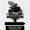 Black metal memorial sign of a winged motorcycle rider above text ribbons reading "Forever Loved," "CUSTOM NAME," and dates "1960-2024" on a white wood background