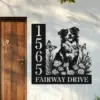Australian-Shepherd-Sitting-with-Butterfly-1-2 Black metal house sign mounted by a wooden door showing address numbers 1565 and text 'FAIRWAY DRIVE' with cutout art of a smiling dog, flowers, and butterflies on a light exterior wall