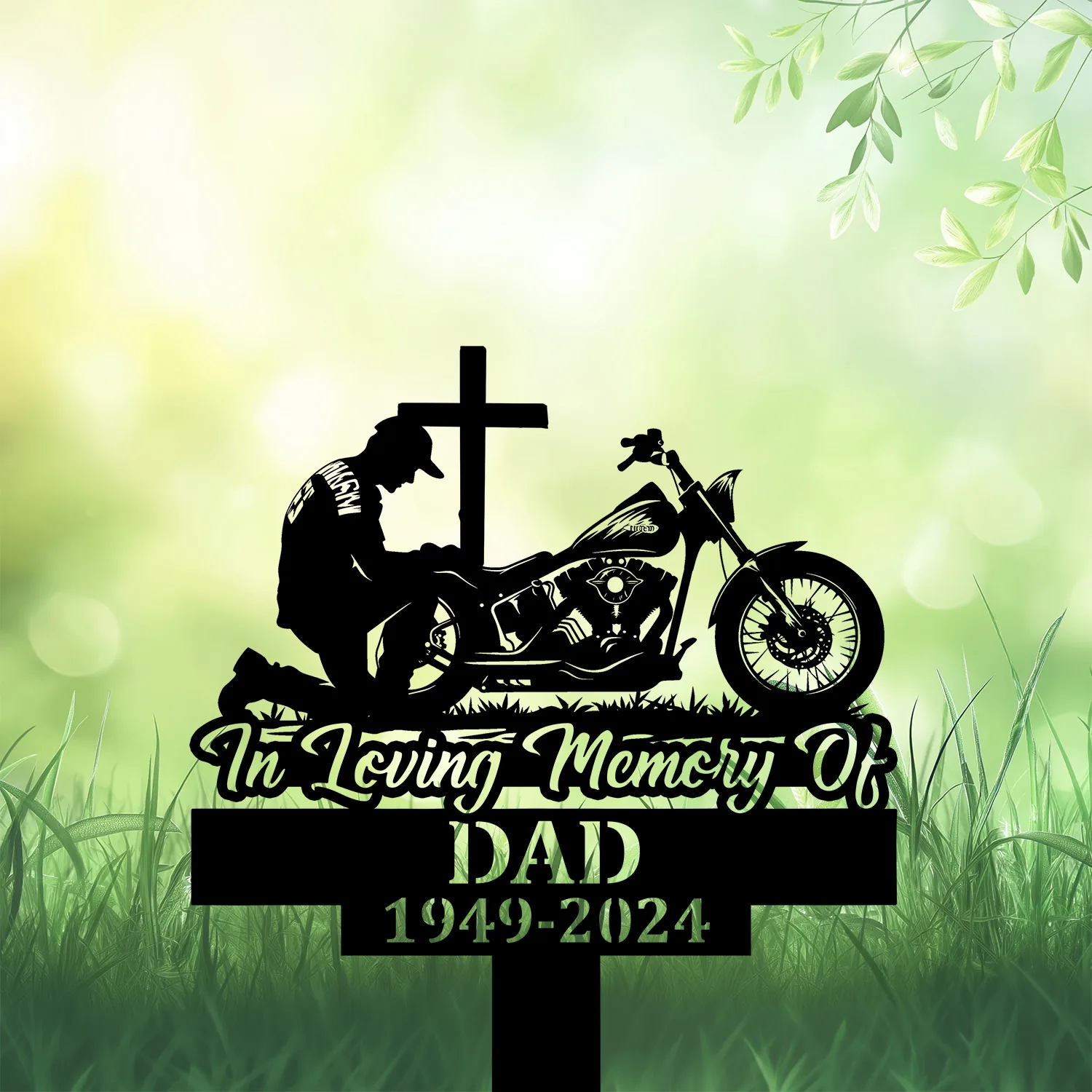 Biker-Kneeling-at-Cross-3 Silhouette memorial sign showing a kneeling motorcyclist beside a cross and bike with text 'In Loving Memory Of' and 'DAD 1949-2024' on a grassy green background.