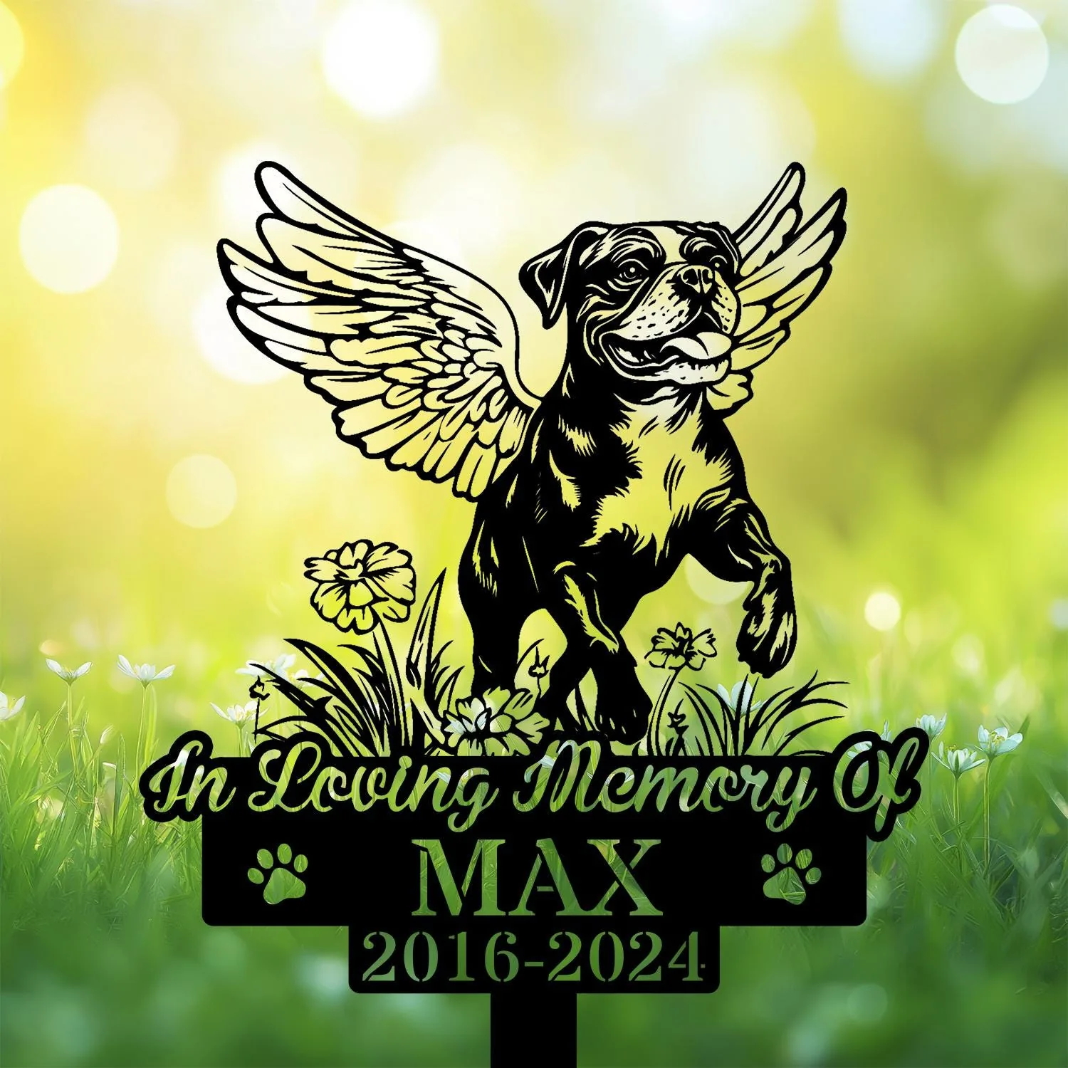 Boxer-7 Black memorial garden stake showing a winged dog above flowers with text "In Loving Memory Of MAX 2016-2024" against a sunlit green bokeh background
