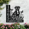 Black metal house sign with address numbers 1565 and text FAIRWAY DRIVE, featuring a sitting dog silhouette, flowers and butterflies mounted on a white brick wall above pink flowering bushes