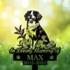 Black silhouette memorial garden stake of a happy dog surrounded by flowers with text "In Loving Memory Of" and name "MAX" and dates 2016-2024 against a sunny green bokeh background