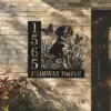 Brittany-Spaniel-Sitting-with-Butterfly-2 Black metal house sign mounted on a brick wall showing numbers 1565 and text FAIRWAY DRIVE with a dog, flowers and butterflies design