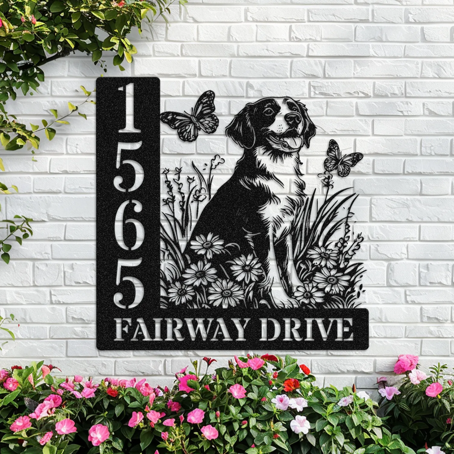 Brittany-Spaniel-Sitting-with-Butterfly-4 Black metal address sign mounted on white brick wall showing numbers 1565 and text FAIRWAY DRIVE with dog and floral cutout and butterflies, pink flowers below