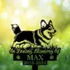 Black silhouette memorial sign of a happy corgi in grass with text "In Loving Memory Of MAX 2016-2024" against a bright bokeh green background