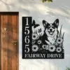 Corgi-Sitting-with-Butterfly-1 Black metal house sign mounted next to a wooden door showing address 1565 and text FAIRWAY DRIVE with a smiling corgi among daisies and butterflies