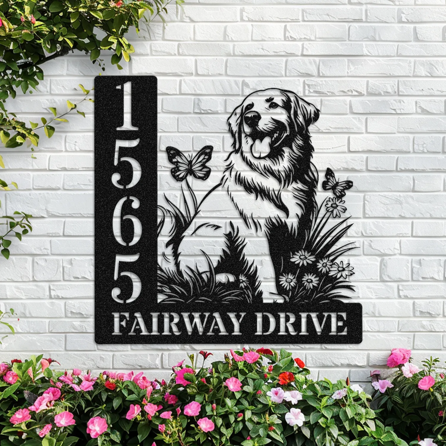 Black metal house sign on white brick with address numbers 1565 and text 'FAIRWAY DRIVE' beside a sitting golden retriever silhouette, butterflies and flowers, with pink blooms below