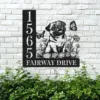 Pug-Sitting-with-Butterfly-2 Black metal house sign mounted on a white brick wall showing numbers 1565 and text ‘FAIRWAY DRIVE’ with a pug illustration, flowers, and butterflies above green shrubs.