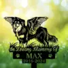 Shetland-Sheepdog-2 Black silhouette memorial sign of a winged dog standing on grass with text "In Loving Memory Of MAX 2016-2024" against a sunlit green bokeh background