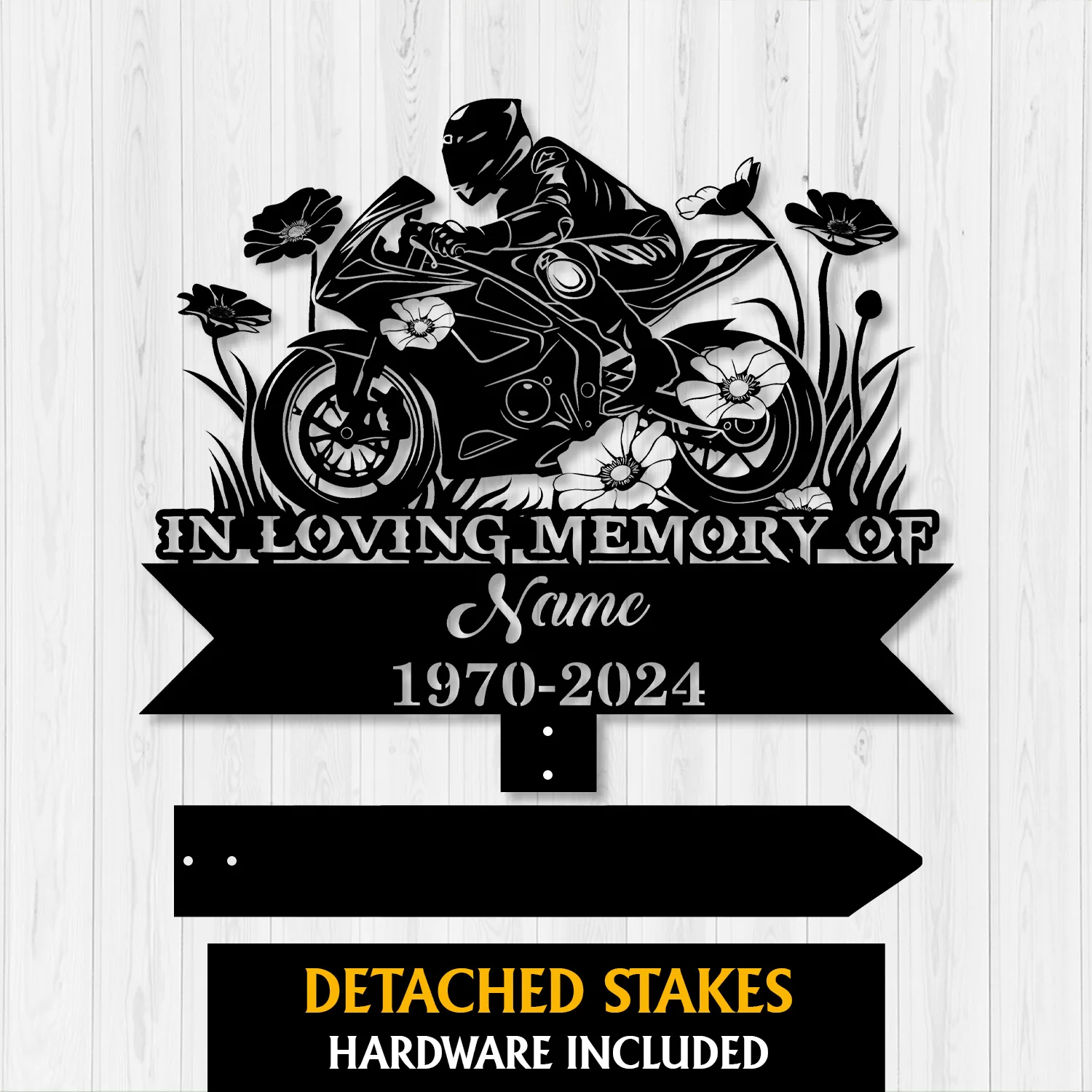 Black metal memorial sign showing a motorcyclist on a sportbike surrounded by flowers, text reading "IN LOVING MEMORY OF", placeholder "Name" and dates "1970-2024", with detached stakes on a light wood background