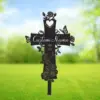 Metal cross lawn stake with roses, butterflies and a heart cutout, showing placeholder text "Custom Name" and dates 1960–2025 against a blurred green outdoor background