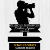 Black silhouette memorial sign of a photographer holding a camera with text "In Loving Memory of" and placeholder "Custom Name 1986-2026" on a light wood background