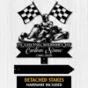 Black metal memorial sign mockup showing a go-kart driver with crossed checkered flags and text reading "In Loving Memory of Custom Name 1986-2026" on a light wood background