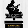 Black silhouette metal memorial sign of a seated person playing guitar with text "In Loving Memory Of" and customizable name and years on a wood panel background
