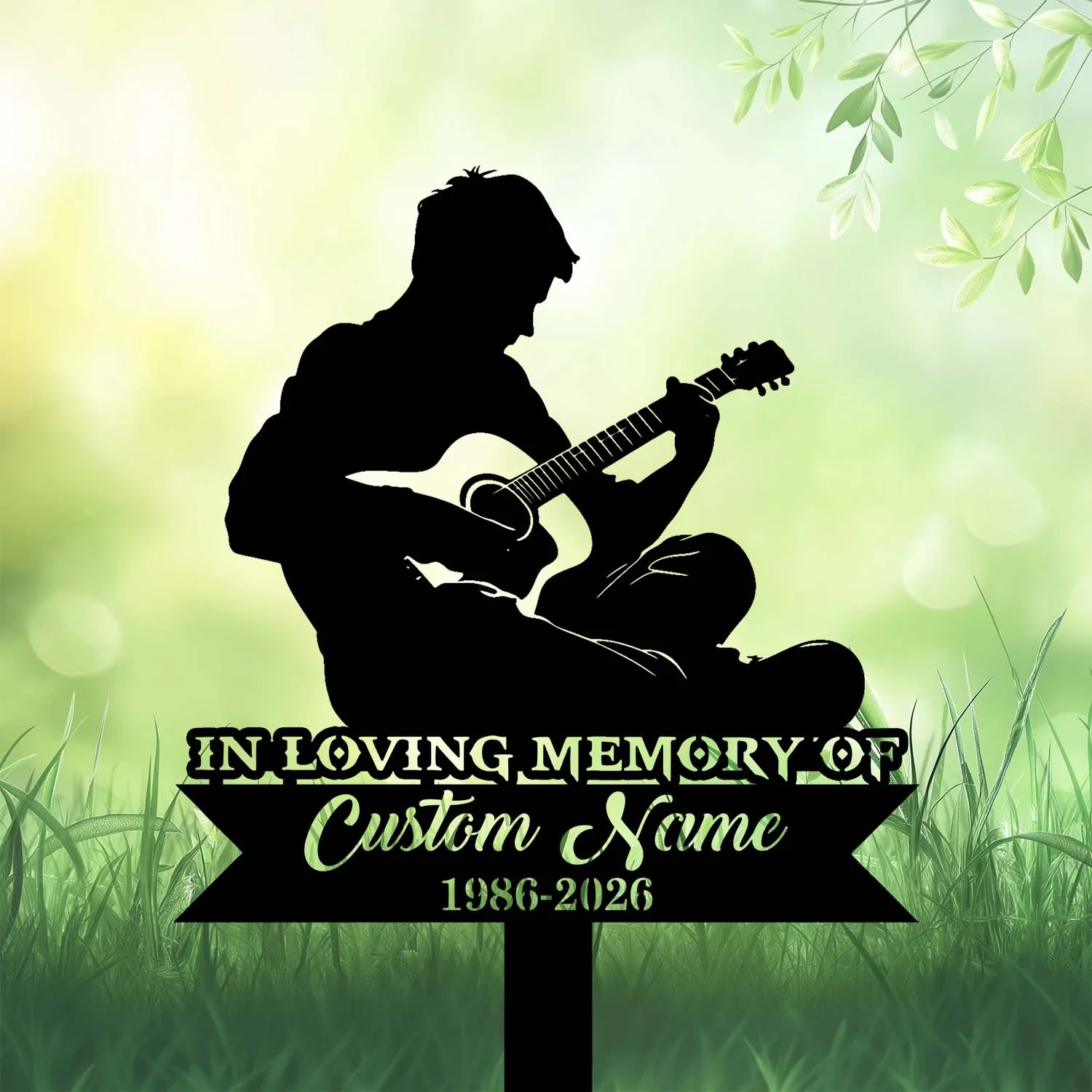 Black silhouette of a seated person playing guitar above a memorial sign reading "In Loving Memory" and space for a custom name and dates against a green grassy background